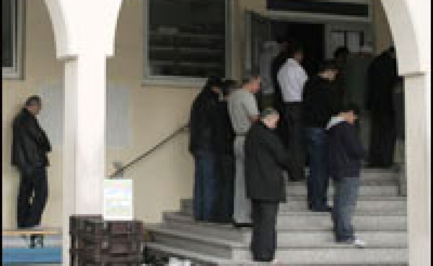 Turkish Muslims participate in Friday prayers outside the crowded prayer room in Cologne. The community's plan to build a large mosque for its members has sparked a heated debate.