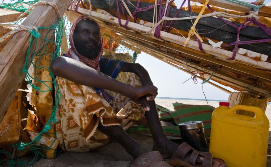 Suleman Ahmen Aden shades himself beneath his fishing raft. Last year, he helped  catch pirates who were forced to beach their boat because of a disabled engine.