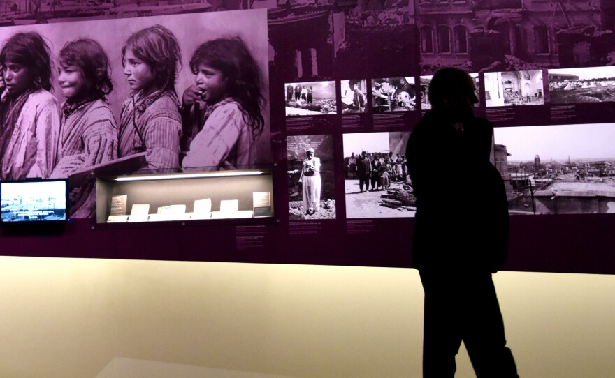 A man walks by photographs at the Armenian Genocide Museum in Yerevan, Armenia, on Tuesday. Armenians will mark the 100th anniversary of the killings on Friday.