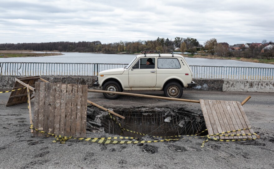 <strong>April 19: </strong>A car passes by a giant hole in a bridge in Makariv, in Ukraine's Kyiv Oblast.