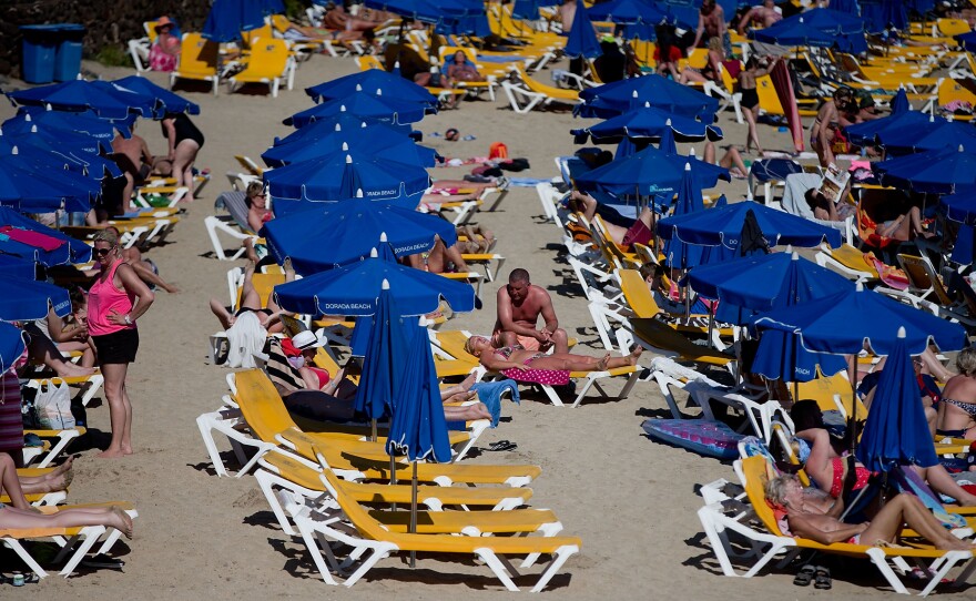 Tourists lay on rows of sun umbrellas on Playa Blaca beach on April 13 in Lanzarote, Spain. Oil exploration began recently in the waters off the coast of the popular tourist destination, despite the opposition of the local residents and government, and environmental organizations.