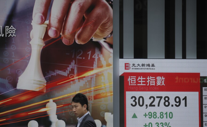 A man walks past an electronic board showing Hong Kong share index outside a local bank in Hong Kong, Wednesday, April 4, 2018. 
