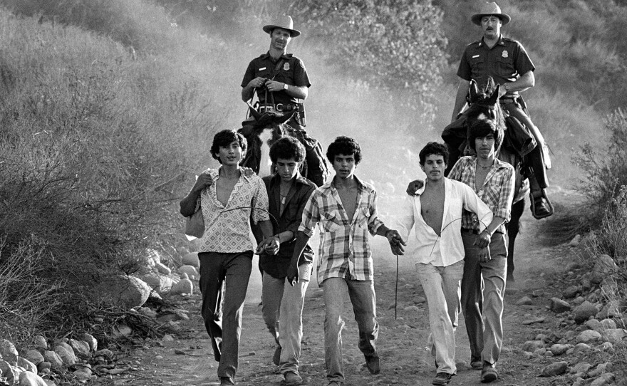 U.S. Border Patrolmen Steve Shields (left) and Ed Pyeatt march five people to a holding center in Texas shortly after their apprehension in the desert in 1981.