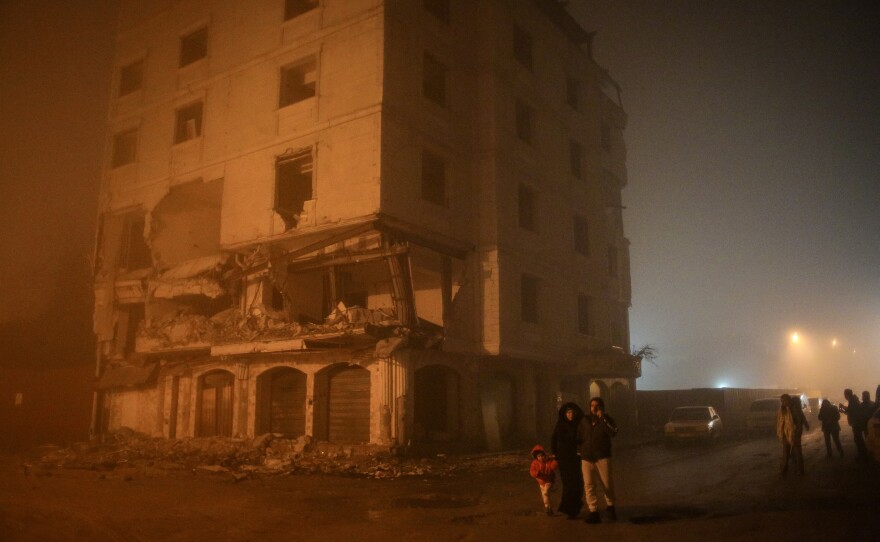 Residents walk by an earthquake-damaged building in Hatay on Monday.