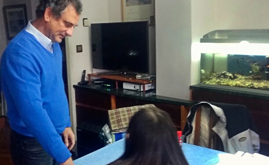 Camilo Jené, 51, watches as his daughter Clara, 14, does her homework at their dining table. She refuses to do homework on weekends now.