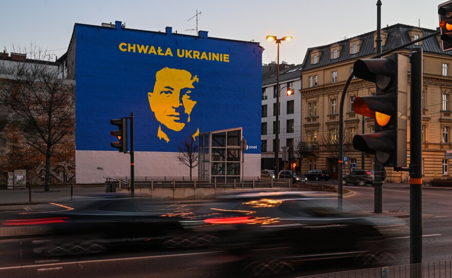 Cars drive past a mural of Ukrainian President Volodymyr Zelenskyy in Krakow, Poland. More than three million people have fled Ukraine since Russia's invasion began in February — many of them to Poland.