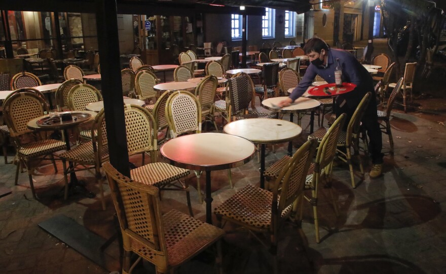 A waiter cleans a table after closing in Saint Germain-en-Laye, west of Paris on Oct. 16,  to comply with new COVID-19 restrictions forcing restaurants, cinemas and theaters in the French capital to close. France imposed a nighttime curfew in Paris and other major cities to curb the spread of the coronavirus.