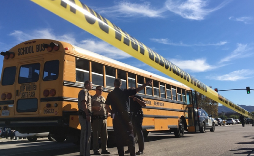 Deputies stand near a school bus in the area of Orange Show Road and Waterman Avenue after multiple people were shot, Dec. 2, 2015.