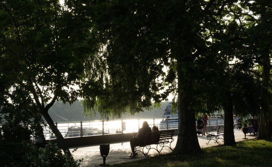 People sit on a park bench watching boats motor up the Danube near the Izmail port.