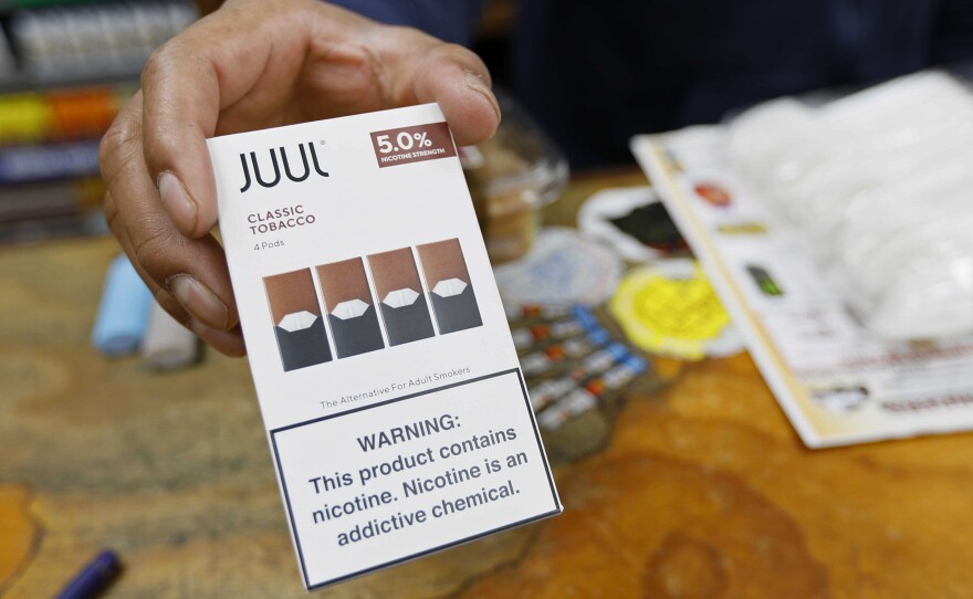 In this June 17, 2019, file photo, a cashier displays a packet of tobacco-flavored Juul pods at a store in San Francisco.