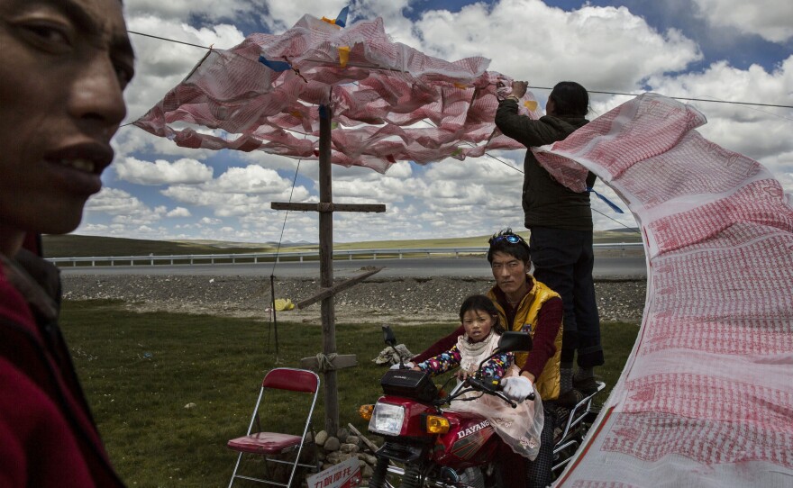 Tibetan nomads put up a string of Buddhist prayer flags in Qinghai, China. They face many challenges to their traditional way of life, including political pressure to resettle, climate change and rapid modernization.