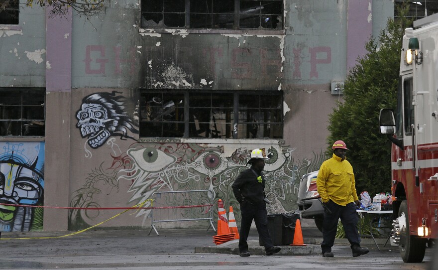Fire officials walk past the Ghost Ship warehouse following the deadly 2016 fire in Oakland.