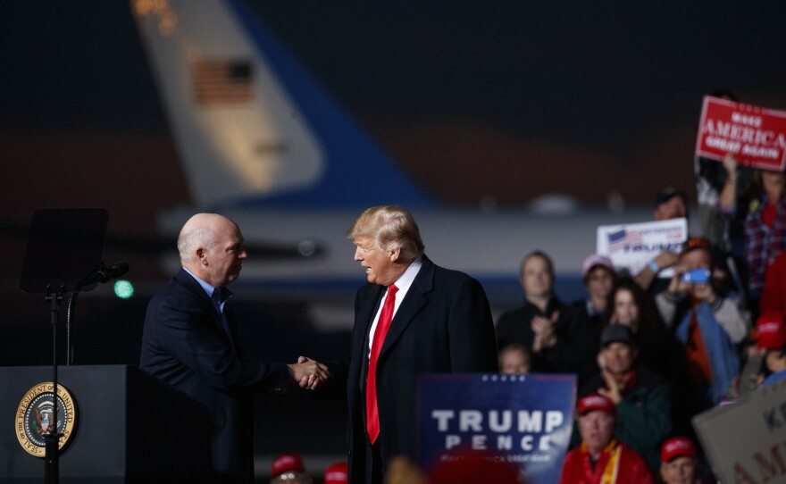 Greg Gianforte, now Montana's Republican governor-elect, and President Donald Trump shake hands on stage during a campaign rally on Oct. 18, 2018, in Missoula, Mont.