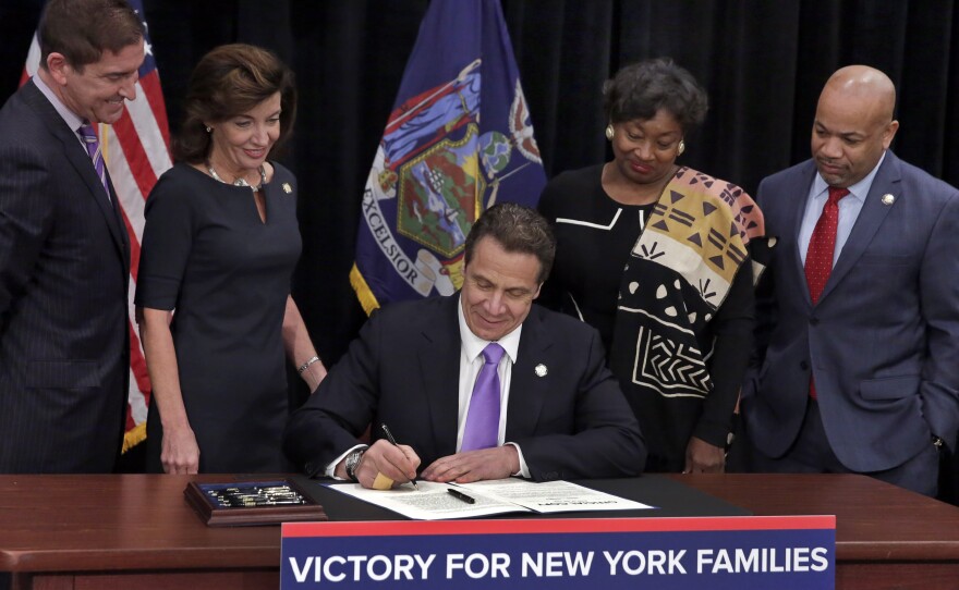 New York Gov. Andrew Cuomo signed a law Monday that will establish a paid-family-leave policy and gradually raise New York's minimum wage, at the Javits Convention Center in New York City.