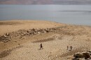 In this Aug. 22, 2021, file photo, a family walks over cracked mud near Lake Oroville's shore as water levels remain low due to continuing drought conditions in Oroville, Calif. 