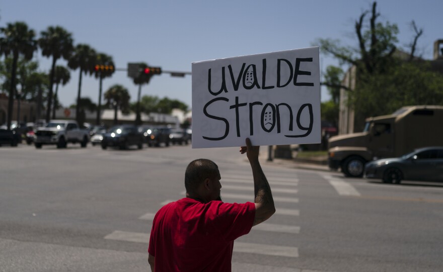 Alex Covarrubias, 32, holds up a sign at a street corner for the victims of Tuesday's shooting Robb Elementary School in Uvalde, Texas, Thursday, May 26, 2022.