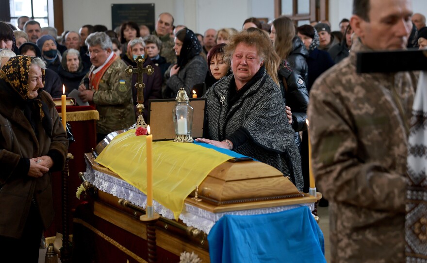 A Ukrainian woman, Maria Korechko, touches the flag-draped casket of her son, Ukrainian soldier Andriy Zagornyakon, during his funeral on April 10, 2022 in Kamianka-Buzka, Ukraine.