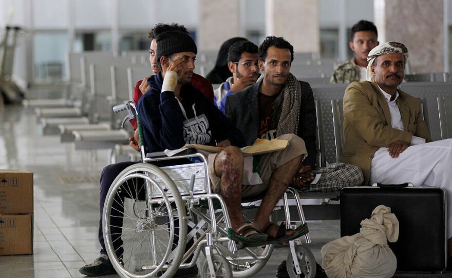 Yemeni men wounded during the airstrike at a funeral sit in the airport in Sanaa on Saturday as they wait for an Omani plane to evacuate them.