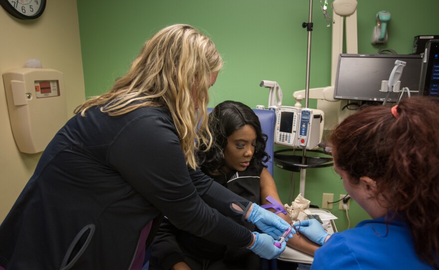 As part of a clinical trial to treat sickle cell disease, Victoria Gray (center) has vials of blood drawn by nurses Bonnie Carroll (left) and Kayla Jordan at TriStar Centennial Medical Center in Nashville, Tenn.