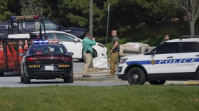 Police talk near the scene of a shooting at a business park in Frederick, Md., Tuesday, April 6, 2021.