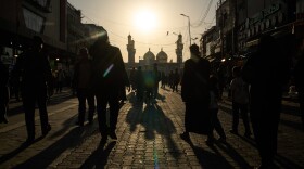 People walk toward the Kadhimiya Shrine at sunset in the Shia neighborhood in Baghdad, Tuesday.