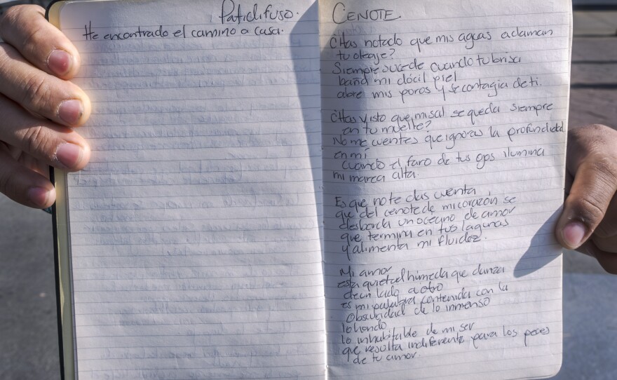 While standing on Tijuana's Avenida Revolución, poet Hugo Velos holds his notebook up with a handwritten poem titled, "Cenote," Dec. 6, 2024. The poem starts: "Mi amor. Esta quietud húmeda que danza. De un lado a otro."