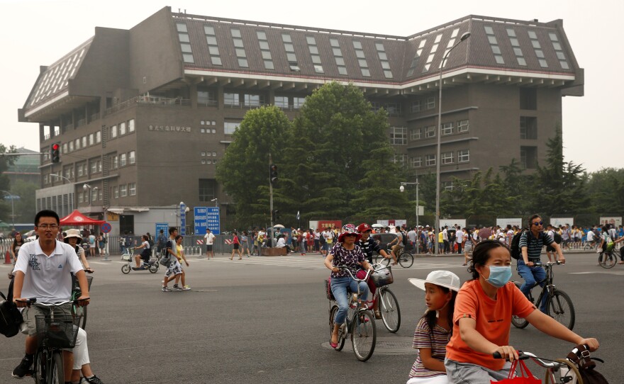 People cycle past a building at Peking University in Beijing in 2016. The university hosts Yenching Academy, a prestigious graduate studies program.