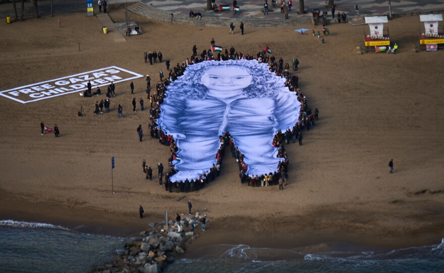 People hold a giant portrait of Hind Rajab, a five-year-old Palestinian girl who was killed during the war in Gaza, on a beach in Barcelona, Spain, Thursday, Jan. 29, 2026.