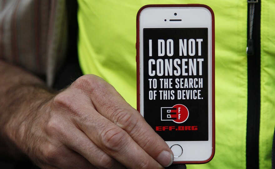 In this 2016 photo, a man holds up his iPhone during a rally in support of data privacy outside the Apple store in San Francisco. Watchdog groups that keep tabs on digital privacy rights are concerned that U.S. Customs and Border Protection agents are searching the phones and other digital devices of international travelers at border checkpoints in U.S. airports.
