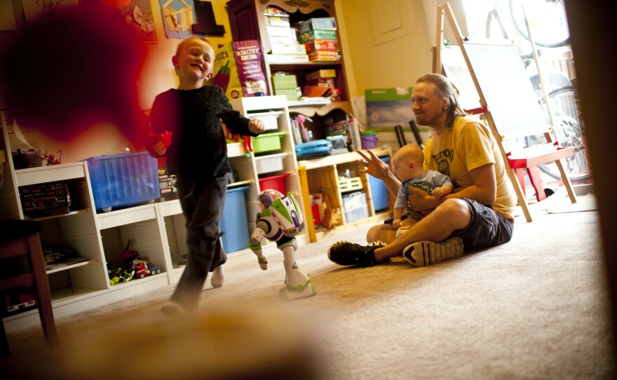 Jonathan holds Zane while Egan runs in the family's playroom.