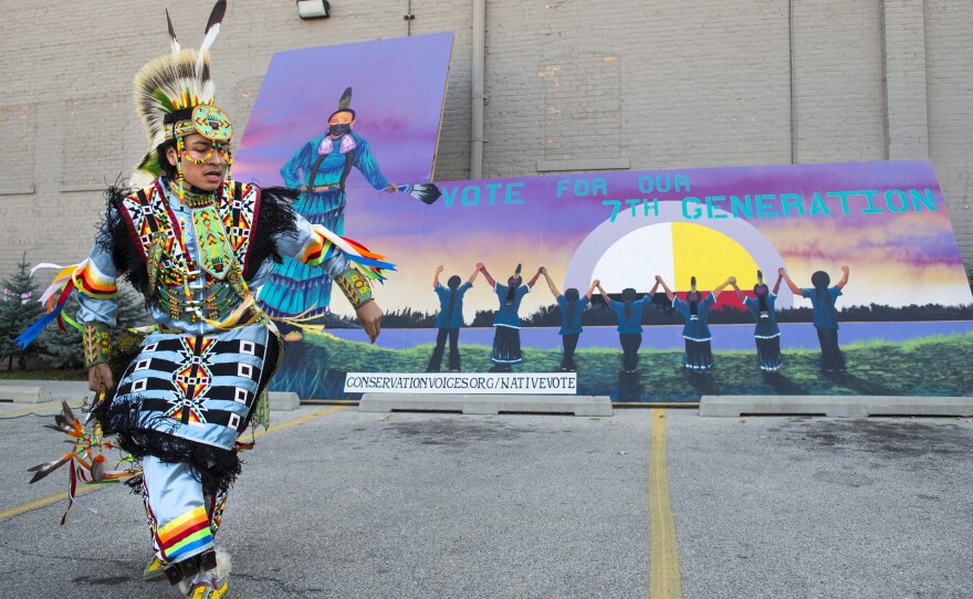 Damian Funmaker performs a traditional Ho-Chunk dance with the Wisconsin Dells Singers and Dancers during an event hosted by Wisconsin Native Vote to encourage voting at the Gerald L. Ignace Indian Health Center in Milwaukee, on Friday. The mural in the background, painted by Christopher Sweet, and reads, "Vote for our 7th generation."
