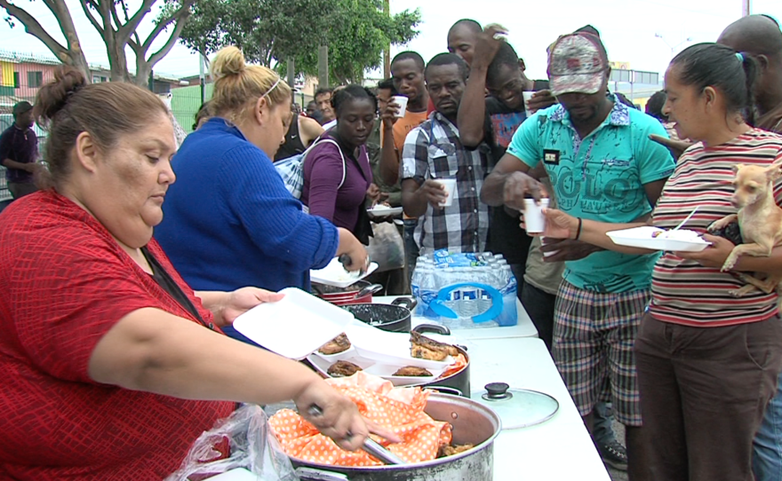 Haitian and African migrants line up for fried chicken, rice and beans in Tijuana, Sept. 19, 2016. 