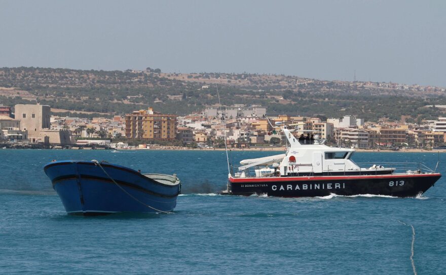 A fishing boat containing the bodies of thirty North African migrants is towed July 1 to the port of Pozzalo on the Italian island of Sicily.