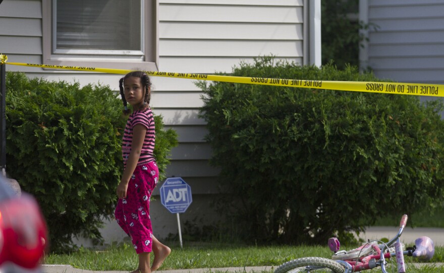 A young neighbor watches as police respond to a double homicide in Flint, Mich., on June 30. Organizations including the Michigan Youth Violence Prevention Center are working to help young people choose non-violent solutions to conflict.