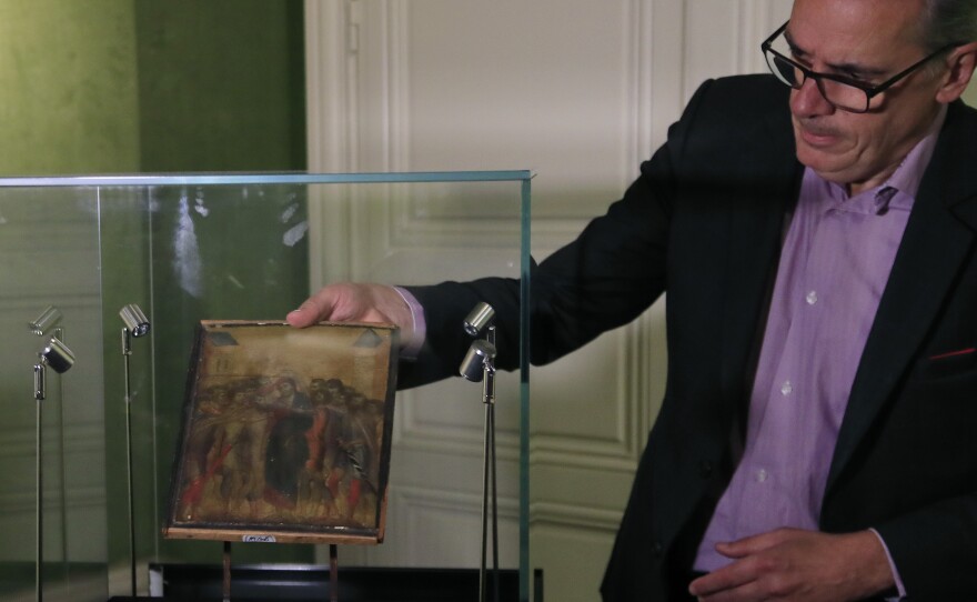 Art expert Stéphane Pinta takes out of a glass case a 13th century painting by Italian master Cimabue in September. That painting, sold for nearly $27 million, is now the subject of a power struggle between an art buyer and the government of France.