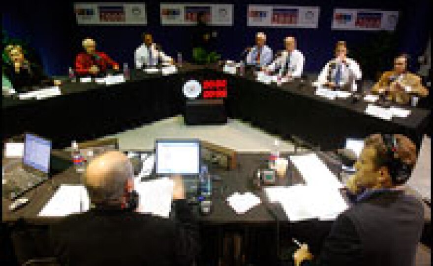 The Democratic presidential candidates sit around a V-shaped table in the Iowa Historical Building during Tuesday's radio debate, broadcast by NPR and Iowa Public Radio. NPR hosts Robert Siegel (left) and Steve Inskeep are visible in the foreground.