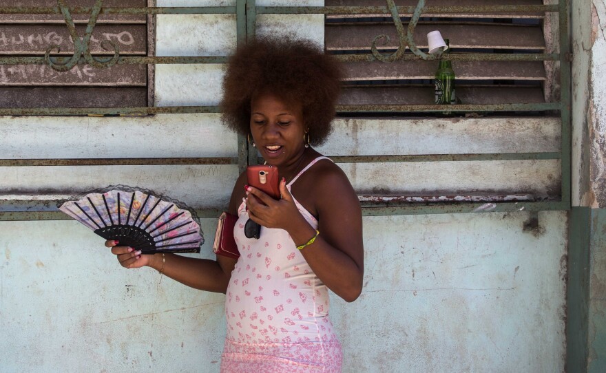 Cuba's telecom monopoly is rolling out broad Internet access for mobile phone users this week. Here, a woman uses her smartphone to surf the Internet in Havana.