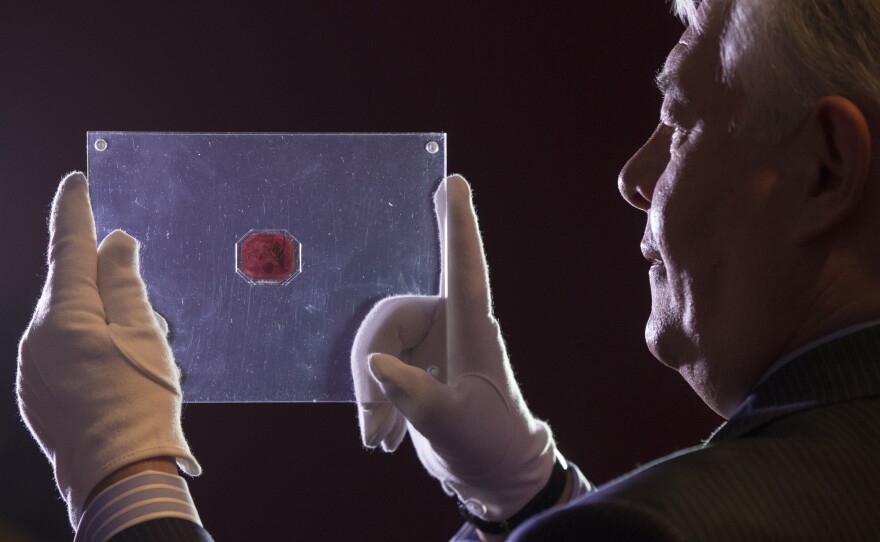 David Redden of Sotheby's auction house holds a case containing the sole-surviving "British Guiana One-Cent Black on Magenta" stamp dating from 1856.