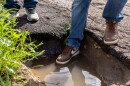 Rob Campbell tests the depth of a pothole on Madrone Avenue in Skyline on Thursday, Feb. 8., 2024 — but stops short when his shoe hits water.