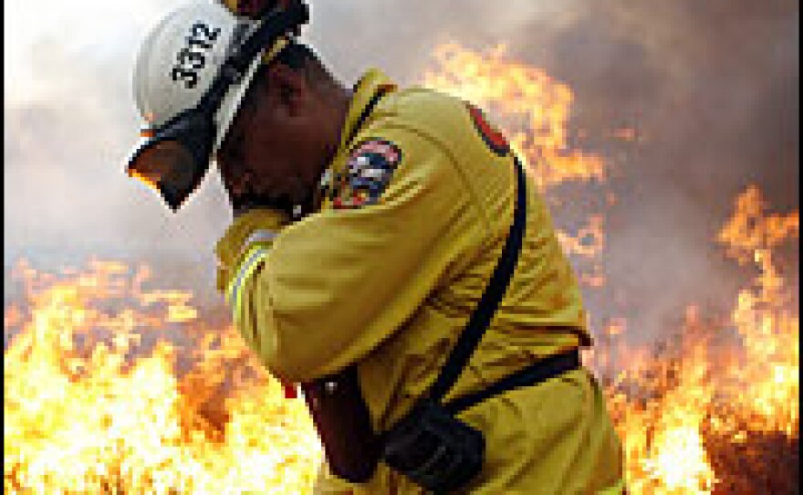 A firefighter lights backfires to protect the neighborhood of Bonita in San Diego, Calif., on Tuesday. Wildfires have forced the evacuation of at least 346,000 homes.