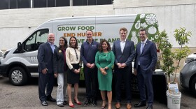 Officials and grant recipients stand in front of a new electric vehicle, March 31, 2026.