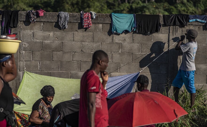 Mostly Haitian migrants wait on the side of a highway for buses provided by the INM.