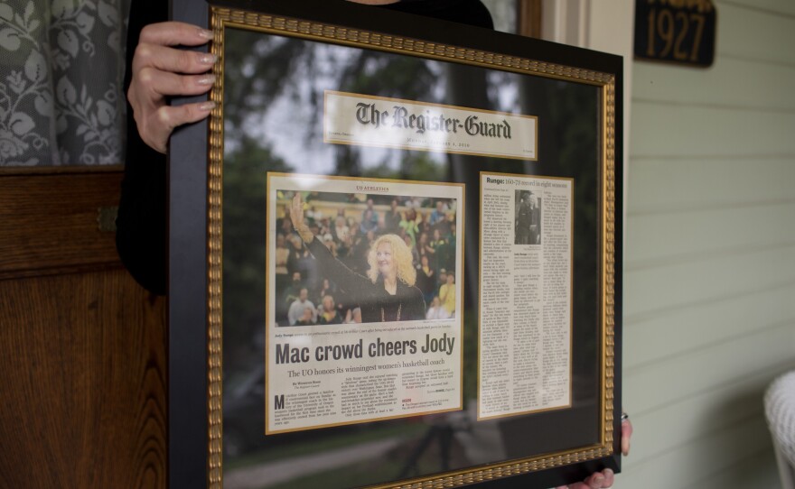 Runge holds a framed newspaper article about returning to UO for the closing of McArthur court.