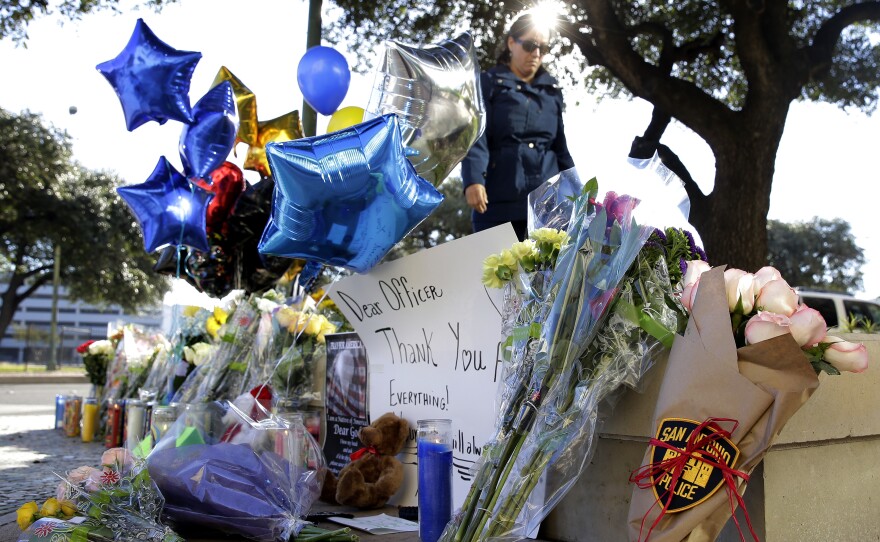 A woman leaves flowers at a makeshift memorial for slain San Antonio police Detective Benjamin Marconi on Monday. Marconi was fatally shot during a traffic stop Sunday near police headquarters.