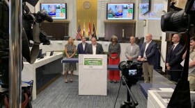 San Diego Foodbank CEO Casey Castillo is shown speaking to the media, surrounded by other local leaders at the County Administration Building on October 30, 2025.