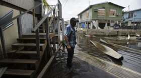 Juana Matos resident Hector Rosa walks through a flooded area after the passing of Hurricane Maria, in Puerto Rico, Wednesday, September 27, 2017. 