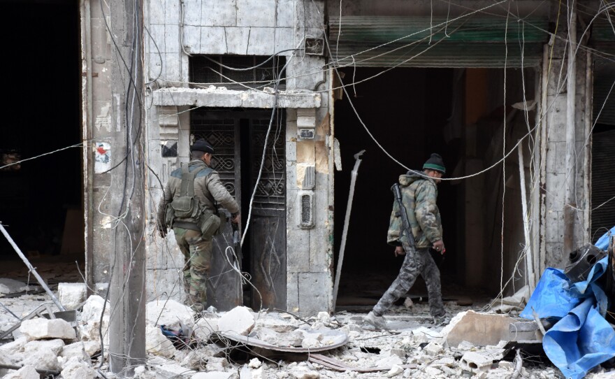 Syrian pro-government forces inspect a building in al-Maadi district of eastern Aleppo on Sunday after they retook a large part of it from rebel fighters.