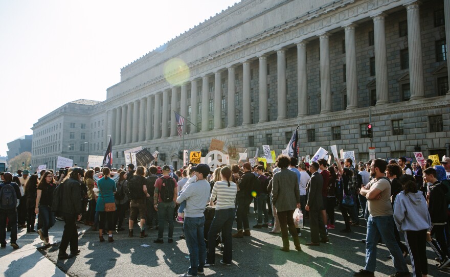Protesters gather along 14th Street outside of the Reagan Building before the start of the press conference.