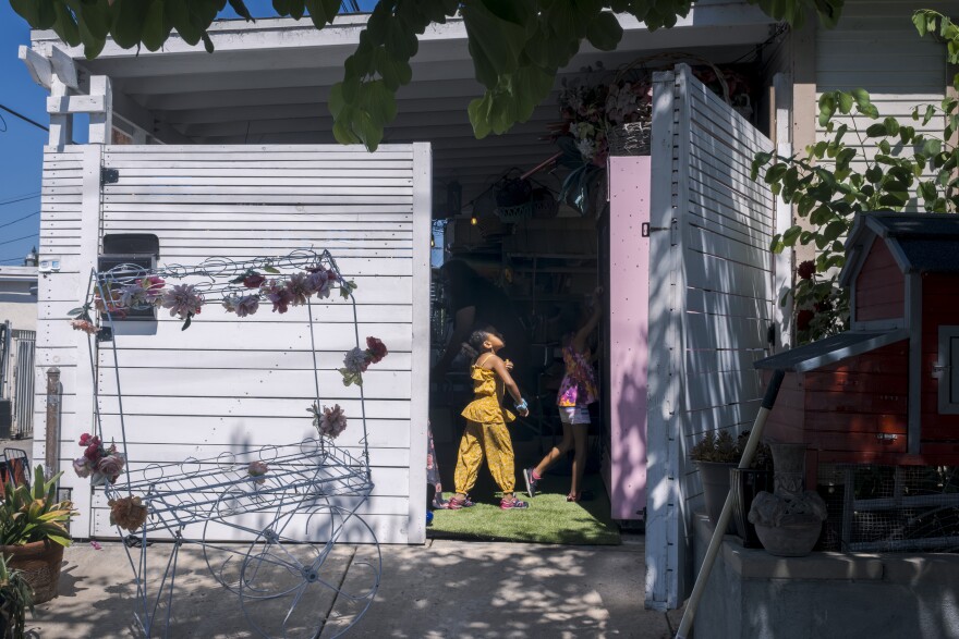 Former neighborhood kids play in in the carport that houses Jackie Jo Flowers in Logan Heights on Monday, Aug. 19, 2024.