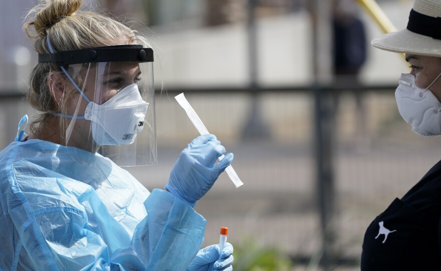 Nurse practitioner Debbi Hinderliter, left, collects a sample from a woman at a coronavirus testing site near the nation's busiest pedestrian border crossing in San Diego. Aug. 13, 2020